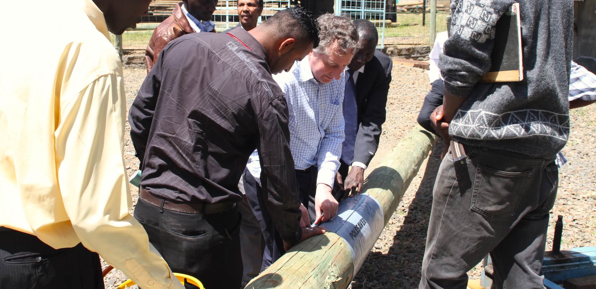 Image showing Polesaver being applied to a utility pole in a yard in West Africa