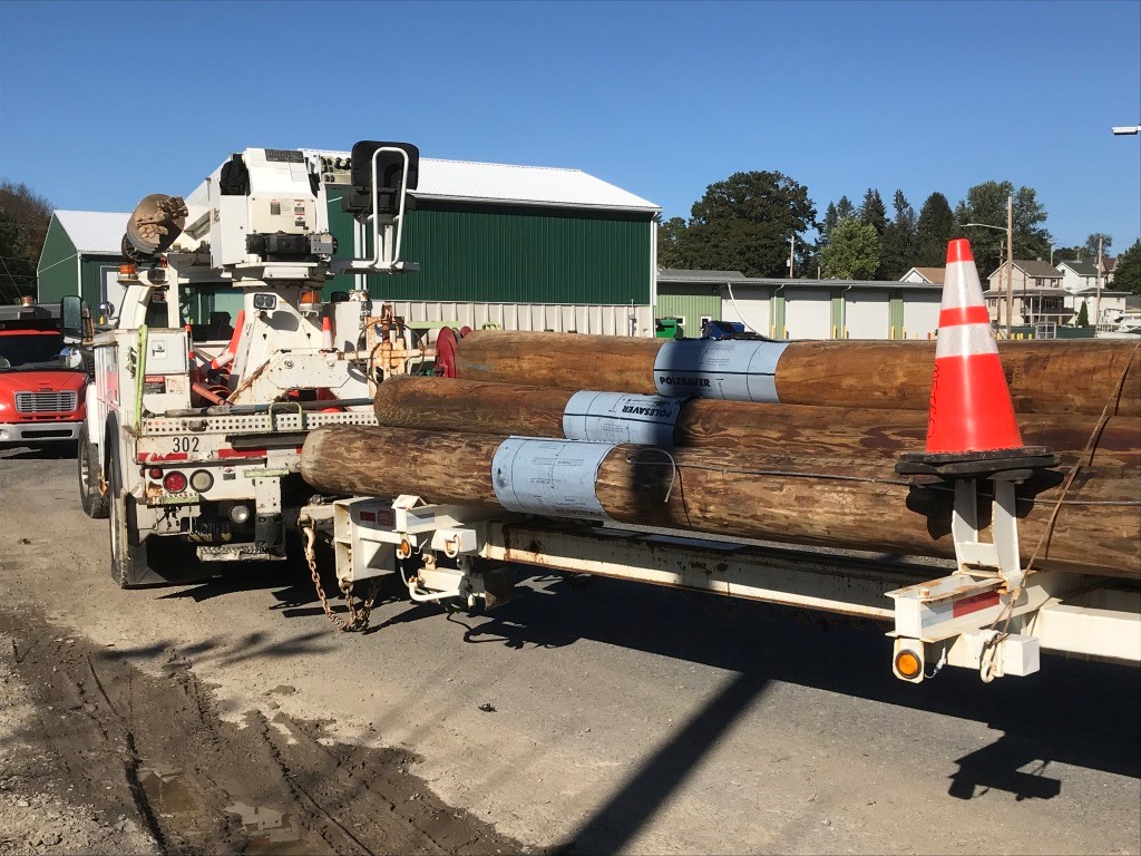 Images showing several utility poles on the back of a truck with Polesaver Sleeves on in use by Lehighton Power and Light, a customer of Polesaver in the USA
