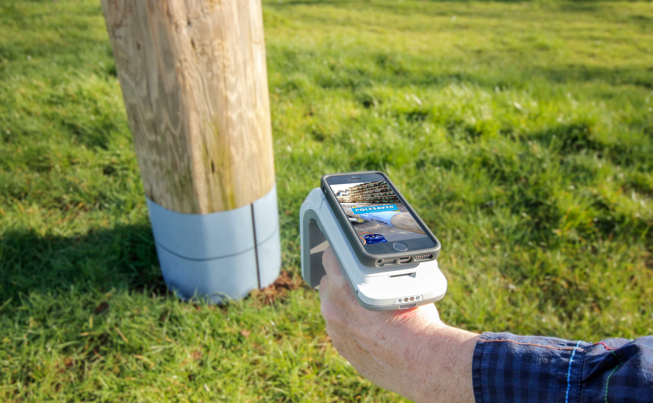 Polesaver RFID Asset Tracking Image Showing Smartphone attached to RFID reader pointed at a wooden utility pole with a polesaver sleeve on