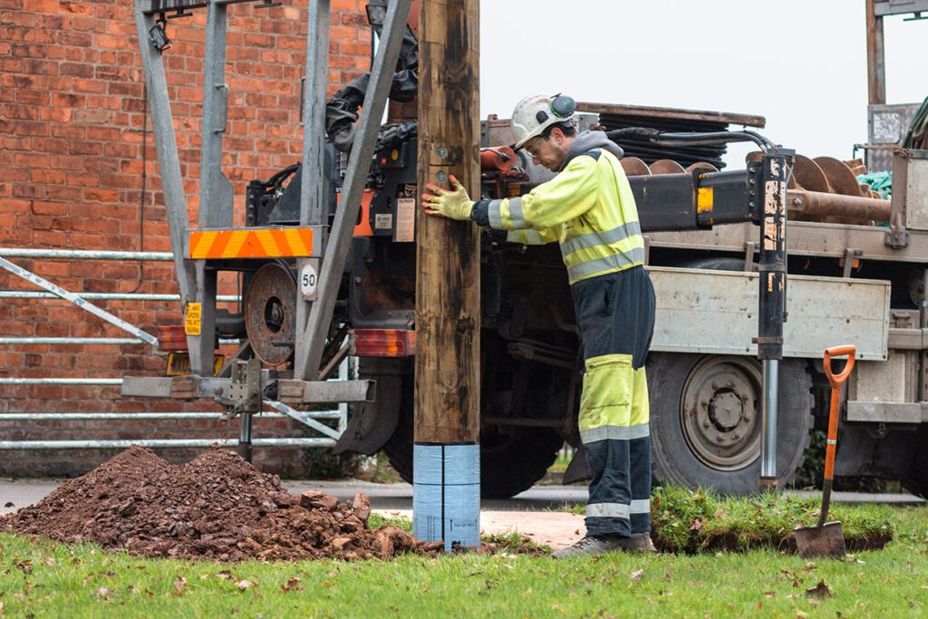 Worker installing Polesaver protected pole