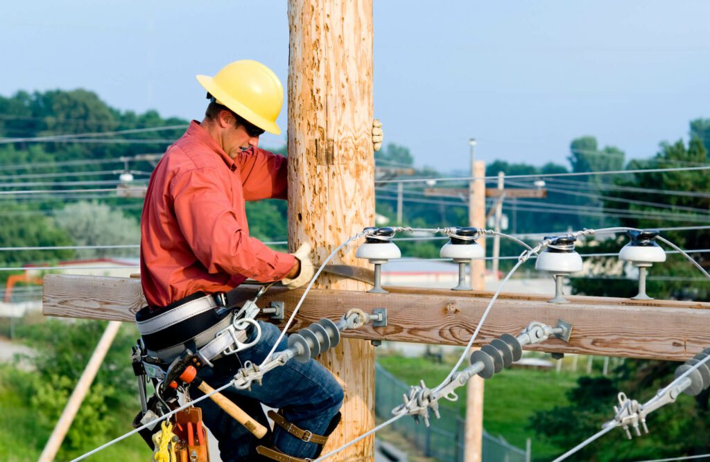 Lineman climbing wooden utility pole to carry out maintenance Lineman climbing wooden utility pole